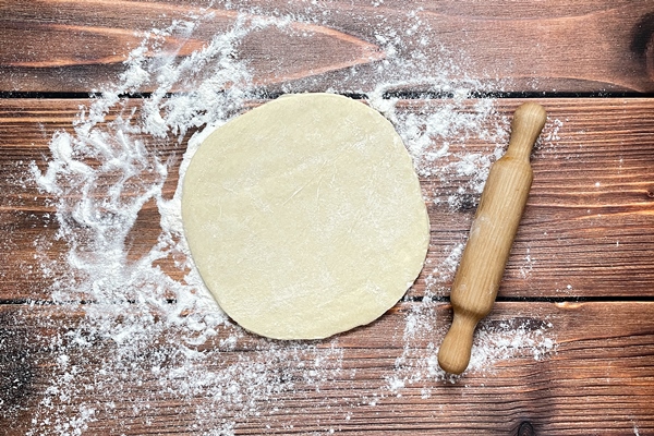 dough rolled out on a wooden table with a rolling pin top view flat lay - Постная галета с помидорами