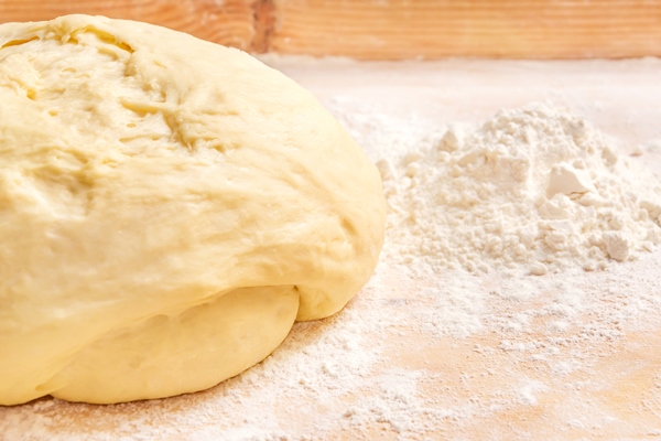dough with a pile of flour on a wooden background - Постная галета с помидорами