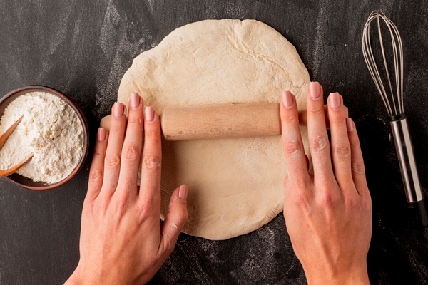hands rolling bread dough with whisk - Постная абрикосовая галета