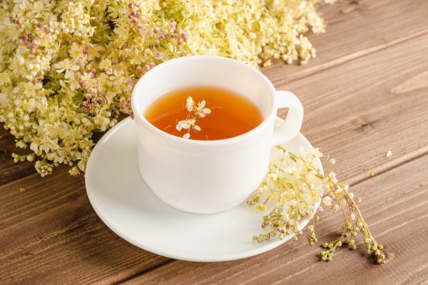 healthy herbal tea with meadowsweet in a white cup on a brown wooden background with a bouquet of meadowsweet - Напиток медовый с таволгой