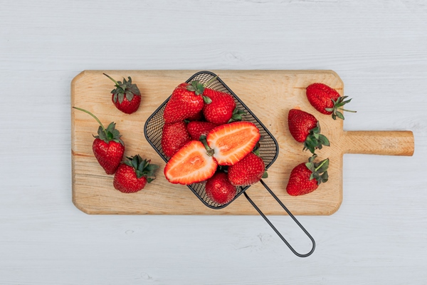 set of several strawberries around it and strawberries in a black basket on a wooden cutting board and white background flat lay - Клубничная галета, постный стол