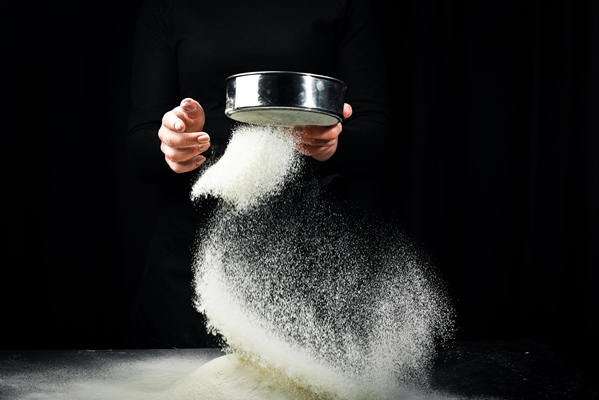 sifting flour through a sieve flour in hands on a dark background - Галета со шпинатом, постная