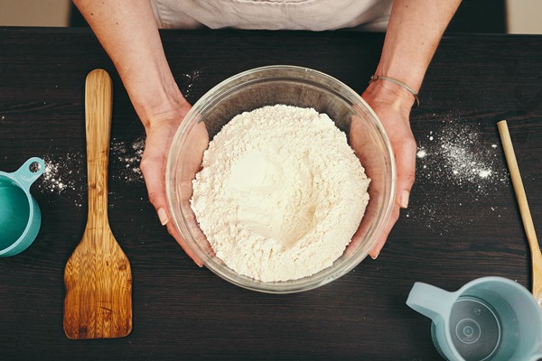 woman hands and bowl of flour for baking above with ingredients or recipe on kitchen counter at home top view of female person or baker hand holding mixture or batter for delicious pastry in house - Постная галета с персиками и малиной