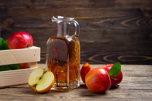 apple cider vinegar and fresh red apple on a wooden background - Яблочный уксус из сока