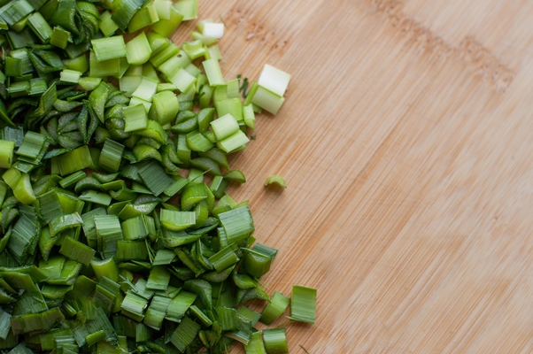 finely chopped fresh green onions on a wooden cutting board with blurred edges - Яблочно-свекольная окрошка