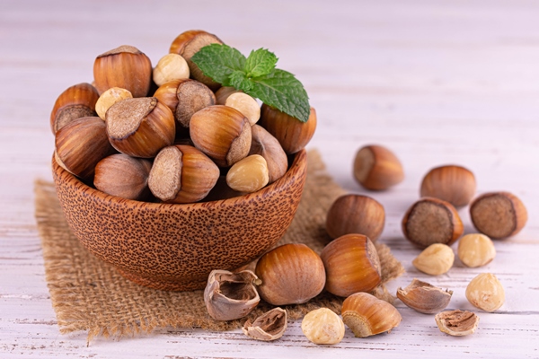 hazelnut organic hazelnuts in a wooden plate on a white wooden background closeup of nuts - Лещина: сроки сбора лесного ореха и рецепт приготовления