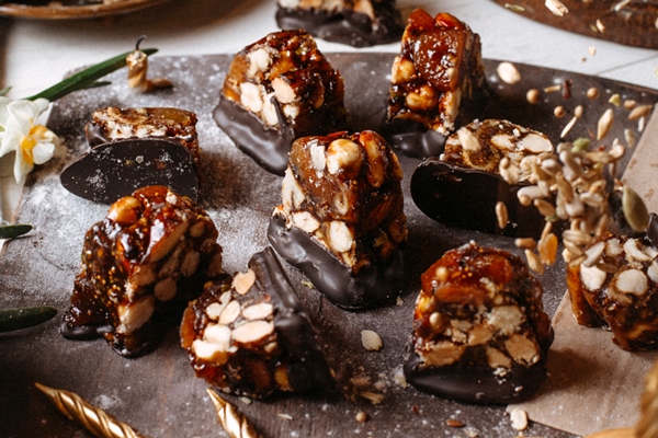side view of candy with caramel dark chocolate and roasted hazelnuts on a wooden board - Лещина: сроки сбора лесного ореха и рецепт приготовления