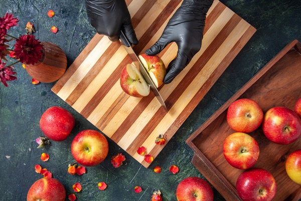 top view female cook cutting apples on gray surface - Монастырский яблочный уксус