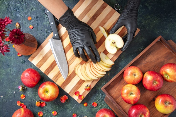 top view female cook cutting apples on the gray surface - Розочки из слоёного теста с яблоками