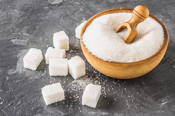white sugar sugar in a wooden plate with a dustpan on a dark background cubes of sugar - Как правильно варить и хранить варенье