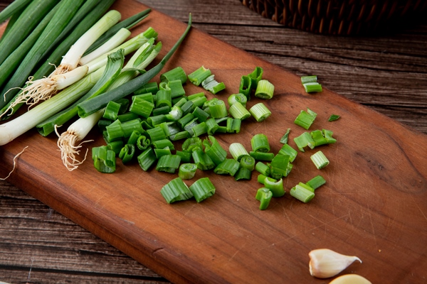 close up view of cut green onion on wooden surface and wooden background - Салат с консервированным тунцом, яйцом, зелёным луком и огурцом