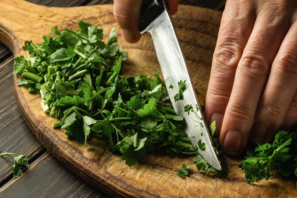 closeup of chef hands cutting green parsley leaves on a cutting board with a knife - Кёнигсбергские клопсы, постный стол