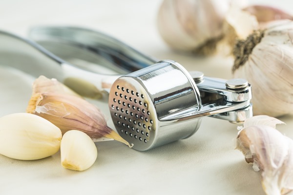 garlic and garlic press on kitchen table - Рулет из лаваша с баклажанами, чесноком и сливочным сыром
