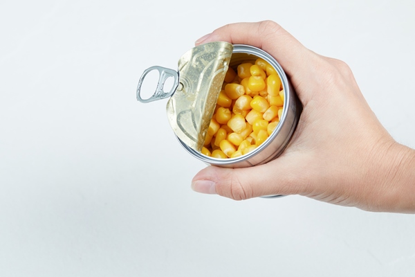 hand holding a tin can of boiled sweet corn - Салат из красной фасоли с кукурузой и помидорами