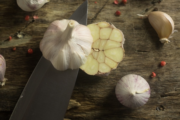 knife cuts garlic on a rustic kitchen board - Хозяйке на заметку: виды кухонных ножей