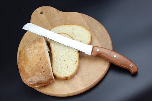 knife is cutting a loaf of bread into slices seed bread homemade breadcutting bread - Хозяйке на заметку: виды кухонных ножей