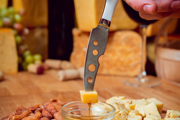knife with piece of cheese on a dark table - Хозяйке на заметку: виды кухонных ножей