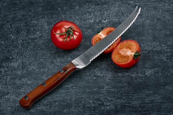 tomatoes and a specialized chefs kitchen tomato knife on a gray grunge background close up - Хозяйке на заметку: виды кухонных ножей