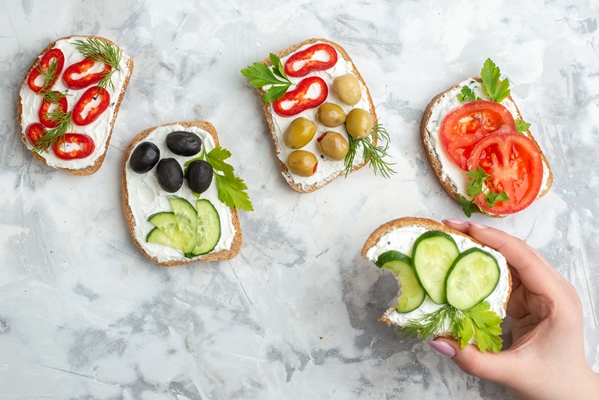 top view different tasty sandwiches with cucumbers tomatoes and olives on white background lunch horizontal food meal bread toast burgers health - Бутерброды с плавленным сыром и овощами