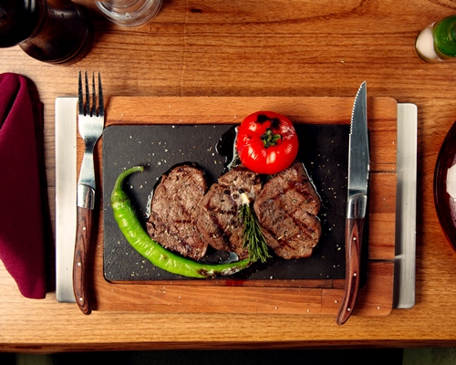 top view of beef steaks served with grilled tomato and pepper - Хозяйке на заметку: виды кухонных ножей