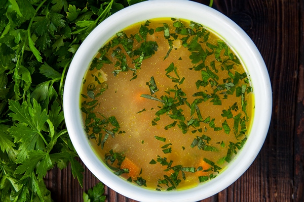 top view soup with vegetables and parsley in a white plate - Сухой овощной бульон