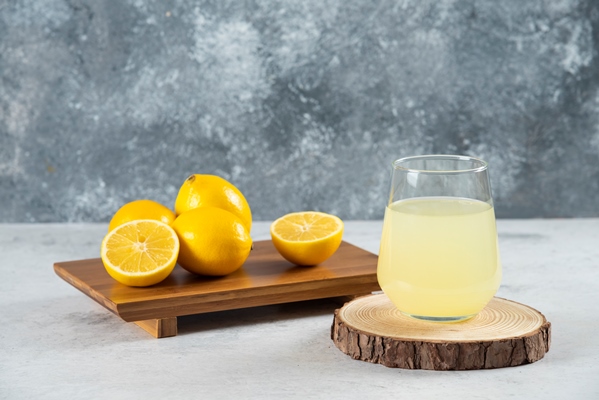 a glass cup of fresh lemon juice on a wooden board - Постная салатная заправка из оливкового масла с пряными травами и мёдом