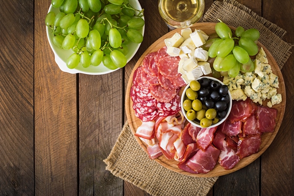 antipasto catering platter with bacon jerky salami cheese and grapes on a wooden table - Православная поминальная трапеза