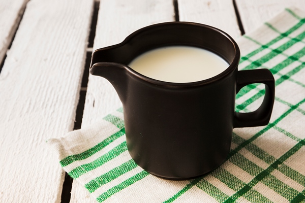 black mug of milk over the napkin on the wooden table - Куркума-латте