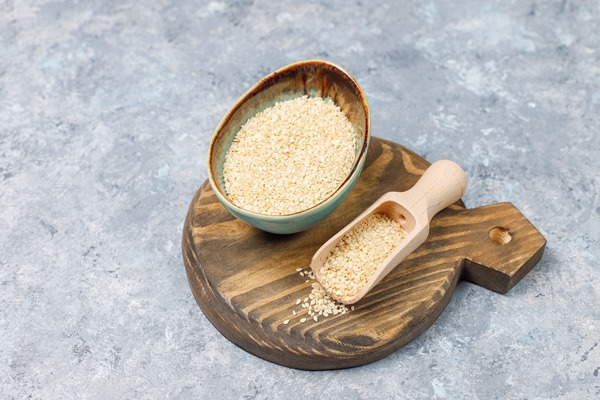bowl of tahini with sesame seeds on concrete surface - Салатная заправка с кунжутом и маком