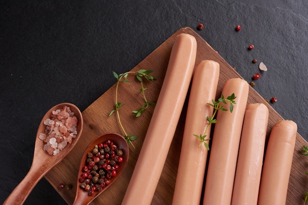 classic boiled meat pork sausages on chopping board with pepper and basil parsley thyme and cherry tomatoes snack for kid black surface sausages with spices and herbs selective focus - Быстрая пицца в микроволновке