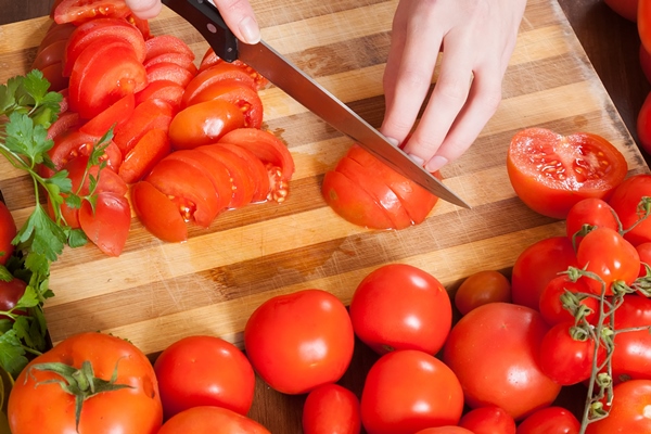 closeup of female hands slicing tomatoes - Салат из свежих помидоров и огурцов (школьное питание)