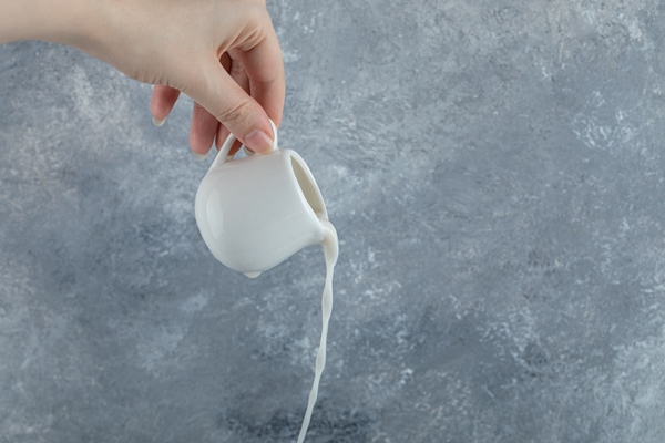 female hand pouring fresh milk out of small mug - Горячая карамель