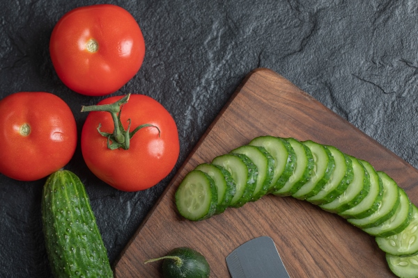 fresh vegetables sliced on a wet black table tomato and cucumber slices on wooden board high quality photo - Огурцы, помидоры, перец болгарский в нарезке (школьное питание)