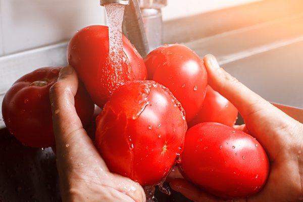 male hands wash tomatoes big tomatoes under water flow part of natural breakfast vitamins are always important - Салат из капусты с огурцами и помидорами (школьное питание)