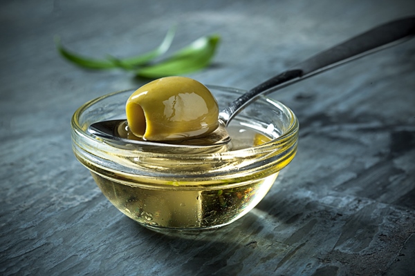 olive oil and olive branch on the wooden table - Салатная заправка с кунжутом и маком
