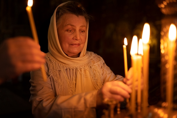 people lighting candles in church in celebration of greek easter - Православная поминальная трапеза