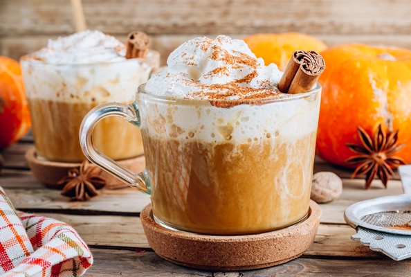 pumpkin spiced latte in a glass mug on a vintage wooden background autumn or winter hot drink selective focus - Тыквенный латте