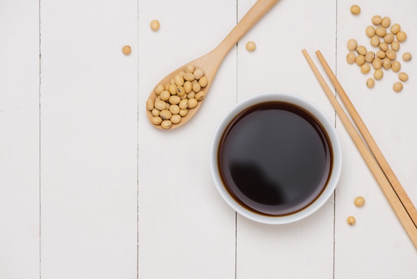 soy sauce and soy bean with chopsticks on wooden table - Салатная заправка с кунжутом и маком