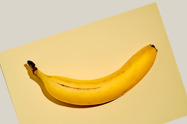 yellow ripe banana on a bright yellow sheet of paper on a light gray background fruit background idea simple things in life - Пшённики с кокосом и бананом