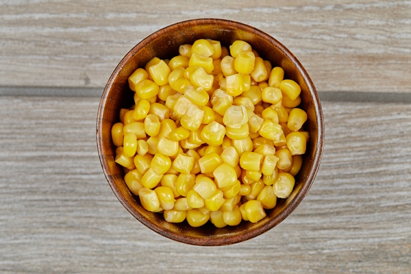 a bowl of boiled sweet corn on a wooden table - Кукуруза сахарная (школьное питание)