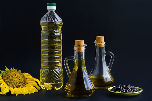 bottle and jug of refined and unrefined sunflower oil yellow flower and seeds - Салат из моркови и яблок (школьное питание)