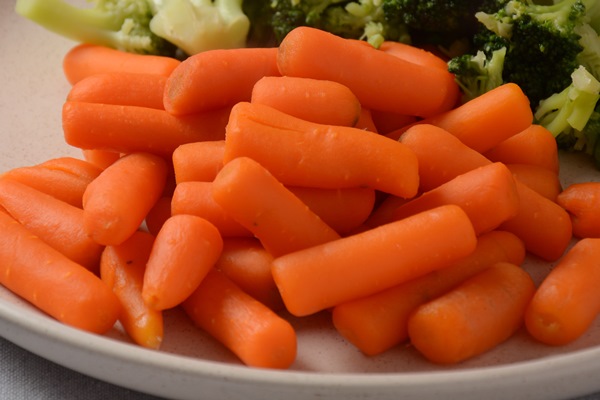 bunch of cooked small boiled carrots and broccoli on white plate healthy eating - Морковь отварная дольками (школьное питание)