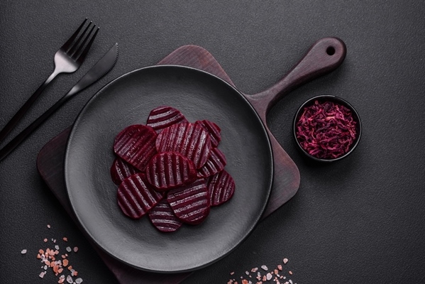 delicious healthy boiled rubycolored beets sliced on a black plate - Свёкла отварная дольками (школьное питание)
