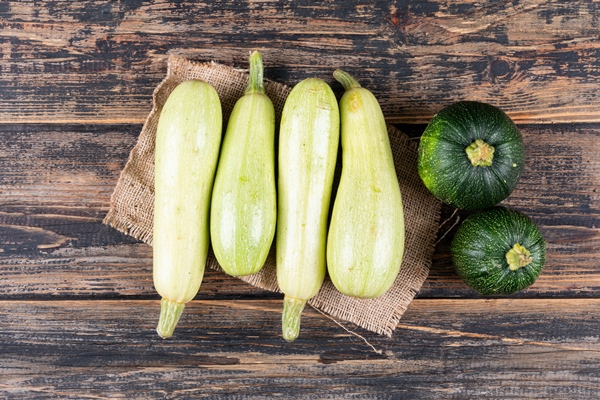 flat lay white and green zucchinis on dark wooden table - Кабачковая икра (школьное питание)