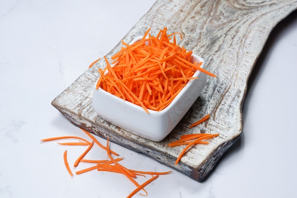 grated carrot in a bowl on white background 1 - Тушёная морковь с изюмом и ламинарией (школьное питание)