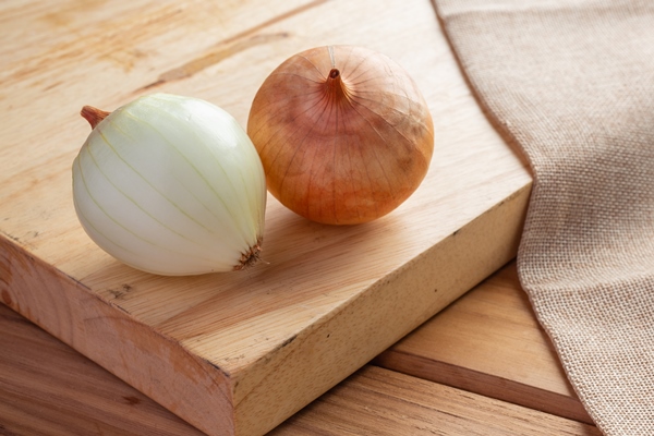two onions on a light brown wood cutting board - Кабачковая икра (школьное питание)