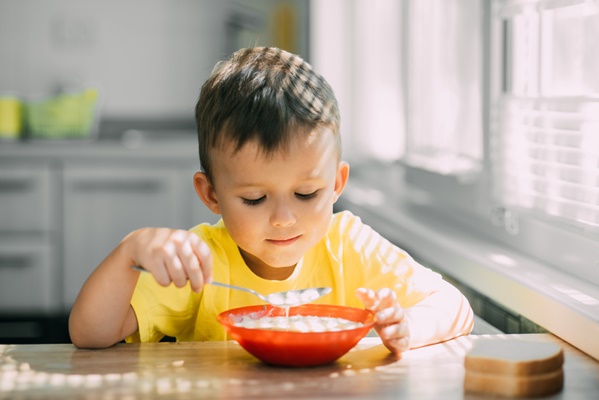 a child in a yellow t shirt in kitchen eating a national russian dish called okroshka - Суп молочный с макаронными изделиями (школьное питание)