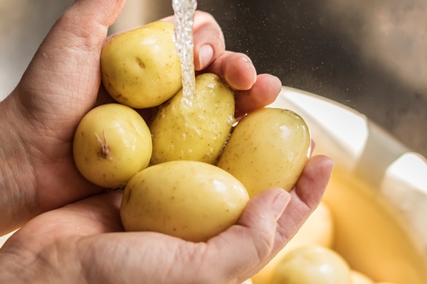 a person washing potatoes under running water food photography recipe idea - Овощной суп (школьное питание)