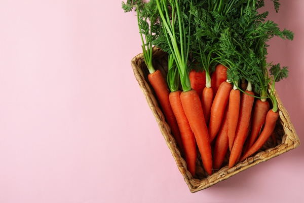 basket with carrot on pink background top view - Макароны отварные с овощами (школьное питание)