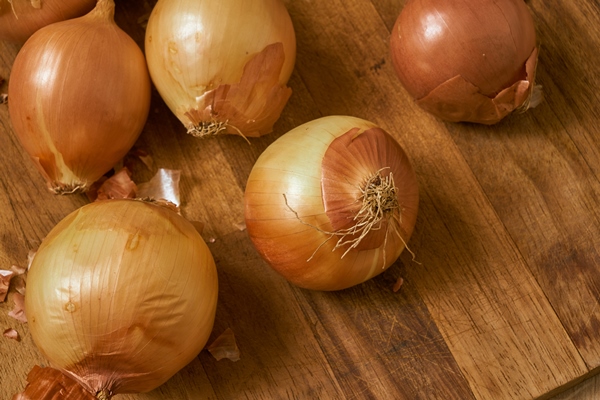 brown onions on a wooden surface with a dramatic light - Овощное рагу (школьное питание)